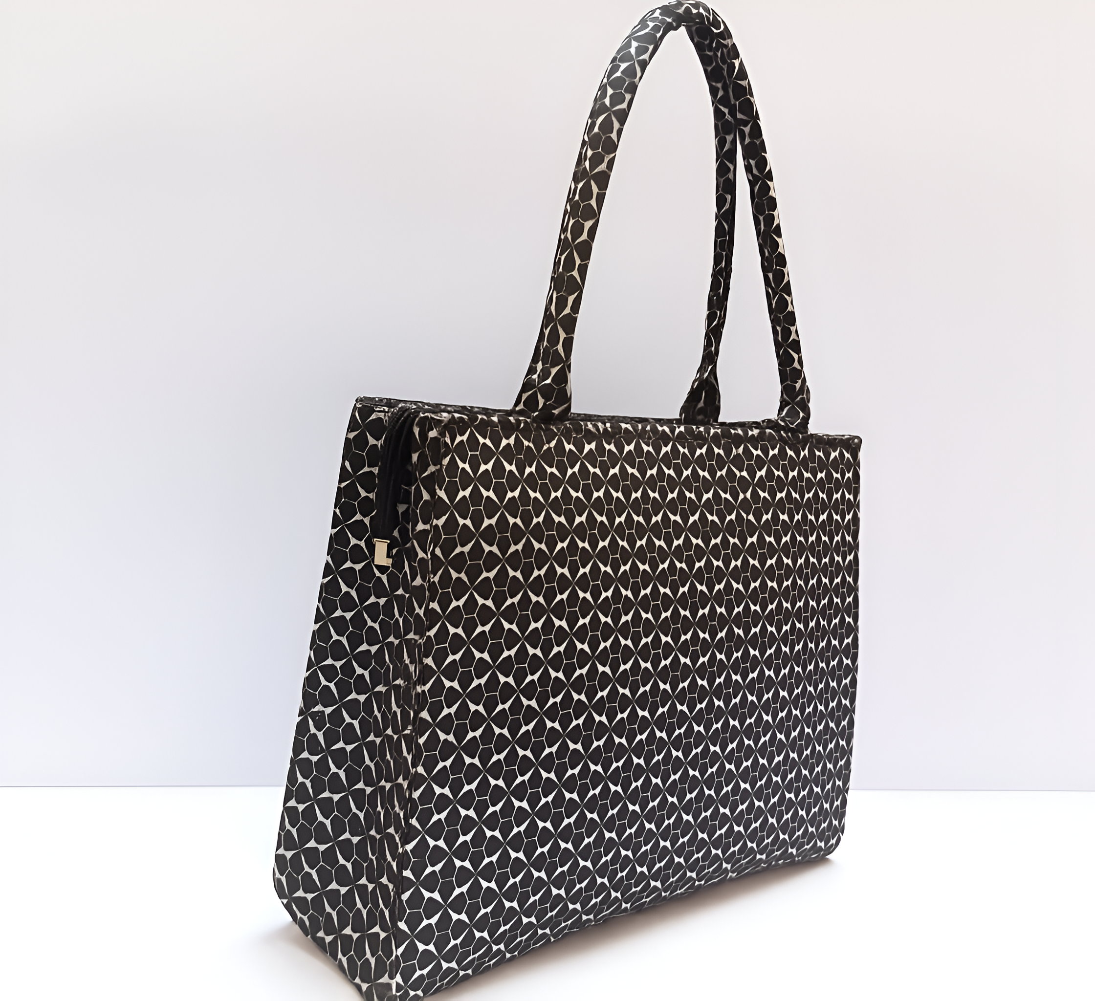 Stylish black patterned canvas tote bag with sturdy handles, set against a plain white background.