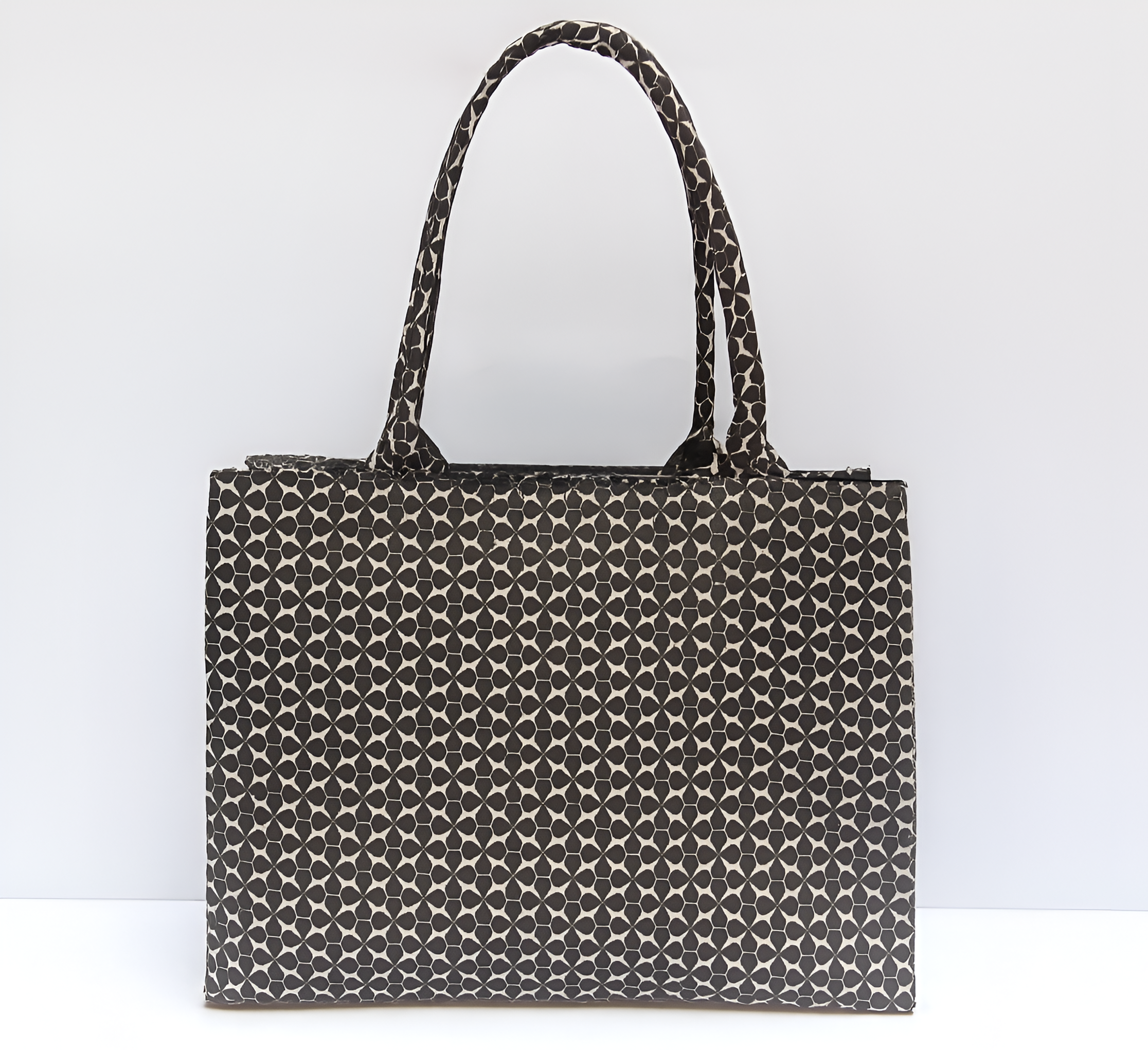 Black and white patterned tote bag with handles displayed against a plain white background.